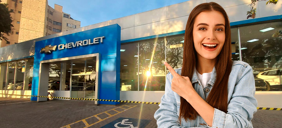 Imagem de uma mulher sorridente apontando para a fachada de uma concessionária na hora de comprar um Chevrolet, enfatizando as promoções e ofertas de veículos