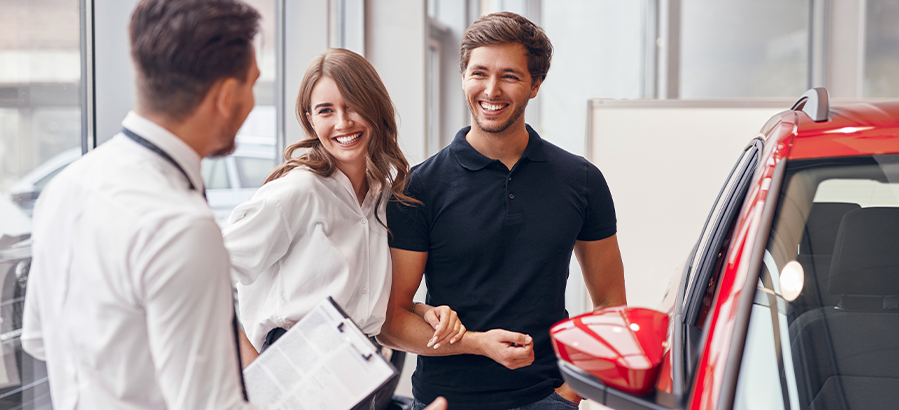 Casal feliz na concessionária de carros depois de usar o simulador de parcelas para calcular seu consórcio Chevrolet.